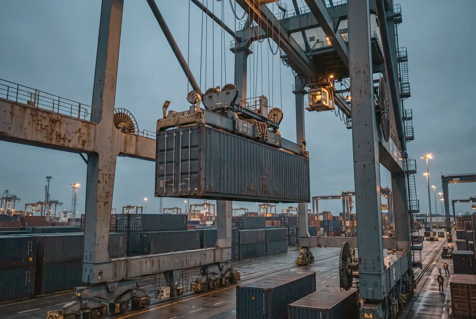 Container lifted by a gantry crane at dusk